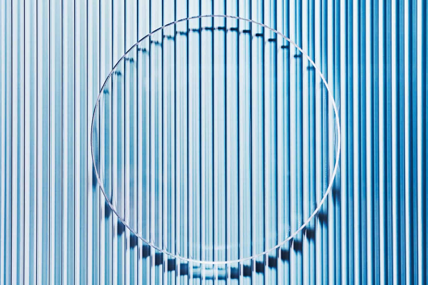 Empty petri dish on blue striped ribbed glass. Mockup for cosmetic product sample