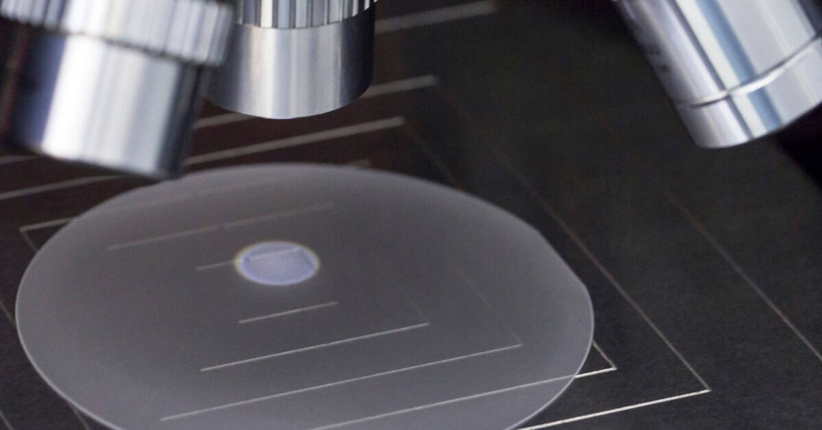 A close-up view shows a sapphire wafer sitting under a microscope. Light from the microscope creates a circle on the wafer.